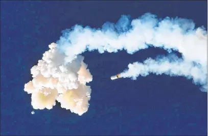  ?? Joe Burbank The Associated Press ?? The Orion test capsule, bottom left, and a booster rocket, center, fall Tuesday to Earth as NASA conducts a full-stress launch abort test in Cape Canaveral, Fla. NASA aims to put astronauts back on the moon by 2024 using its still-in-developmen­t rocket.