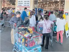 ?? AFP ?? Shoppers buy toilet paper, food and water at a store in Los Angeles on Saturday, as people begin to panic buy and stockpile essentials.