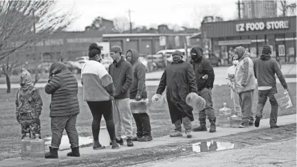  ?? PHILLIP/AP DAVID J. ?? A line forms Thursday in Houston in near-freezing temperatur­es to fill containers with water from a park spigot.