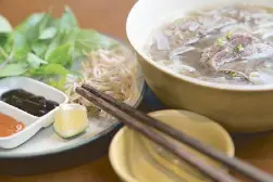  ??  ?? Nha Em’s pho bo (beef noodle soup) is a labor of love. The broth is simmered for 24 hours to extract the flavors out of the beef bones.