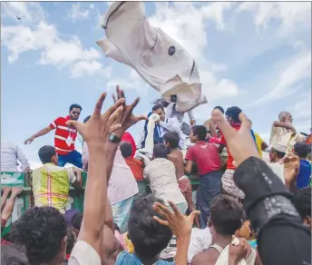  ?? AP PHOTO ?? Rohingya Muslim children, who recently crossed over from Myanmar into Bangladesh, reach out to catch clothes thrown toward them by locals near Balukhali refugee camp in Bangladesh.