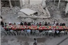  ?? — AFP ?? Syrian residents of the rebel-held town of Douma, on the outskirts of the capital Damascus, break their fast with the ‘iftar’ meal on a heavily damaged street