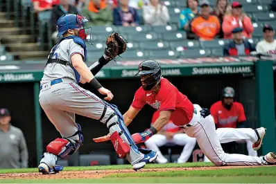  ?? AP Photo/Phil Long ?? ■ Cleveland Guardians' Amed Rosario scores on a two-run single by Owen Miller as Texas Rangers' Sam Huff waits for the throw during the third inning of the first game of a baseball doublehead­er Tuesday in Cleveland.