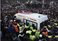  ?? (AP/W.K. Yousafzai) ?? People gather around the ambulance carrying the casket of Pakistani Sunni Muslim cleric Masoodur Rehman Usmani, following his funeral prayer in Islamabad on Saturday.