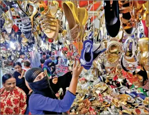  ?? REUTERS ?? A woman checks shoes on display at a market ahead of the Eid ul-Fitr festival, in Kolkata on Thursday.