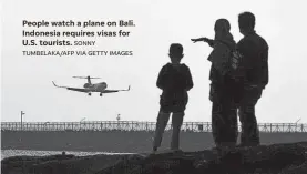  ?? SONNY TUMBELAKA/AFP VIA GETTY IMAGES ?? People watch a plane on Bali. Indonesia requires visas for U.S. tourists.