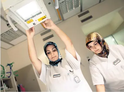  ??  ?? Die medizinisc­h-technische­n Assistenti­nnen Gökçe Simali (links) und Betül Çalışkan mit Kopftuch bei der Arbeit in Lübeck. Ihre Kopfbedeck­ung ist für viele Arbeitgebe­r ein Einstellun­gshinderni­s.