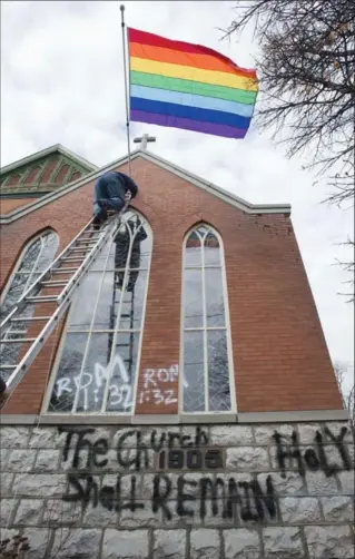  ?? MATHEW MCCARTHY, RECORD STAFF ?? Doug Jacklin places a new pride flag on Emmanuel United Church in Waterloo, Saturday. The church was vandalized earlier this week.