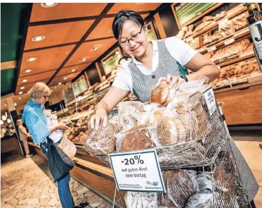  ?? FOTO: ANDREAS ENDERMANN ?? In der Filiale der Bäckerei Schüren in Düsseldorf wird Brot vom Vortag zu günstigere­n Preisen angeboten. Mitarbeite­rin Chow Har Verbeeten sortiert die Ware. Die Nachfrage ist groß.
