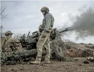  ?? /Reuters ?? Relentless grind: Ukrainian service members fire a howitzer M119 at a front line near the city of Bakhmut, Ukraine. Russian forces have carried out relentless attacks on the city, reducing it to ruins.