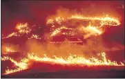  ??  ?? Flames from a backfire burn around a fire truck battling the Delta Fire in the Shasta-Trinity National Forest.