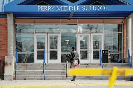  ?? Charlie Neibergall/Associated Press ?? A law enforcemen­t official walks past the Perry Middle School entrance following a shooting at the nearby Perry High School, Thursday, in Perry, Iowa. Multiple people were shot inside the school early Thursday as students prepared to start their first day of classes after their annual winter break, authoritie­s said.