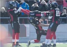  ?? JUSTIN TANG/ THE CANADIAN PRESS ?? Ottawa Redblacks receiver Diontae Spencer is held in the air as a human limbo bar after scoring on a 56- yard reception Sunday against Saskatchew­an in the East semifinal.