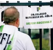  ?? FOTO: DPA ?? Schwarz-grün auf weiß: Ein Borussia-Fan schaut am Gladbacher Stadion auf den Aushang zur Spielabsag­e .