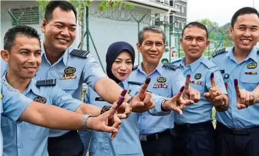  ??  ?? Doing their part: TUDM officers posing for a photo after casting their ballots at Dewan Angkasaray­a at the Sendayan base. — Bernama