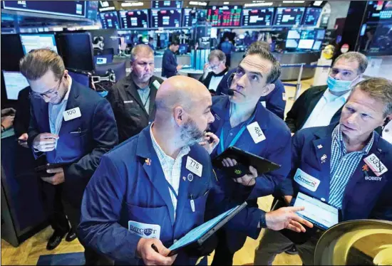  ??  ?? Traders gather on the floor of the New York Stock Exchange, Friday, July 16, 2021. Stocks edged lower Friday, dragged down by a slide from technology companies, as investors digest another round of corporate earnings. (AP)