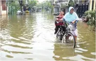  ??  ?? DEMI ANAK: Seorang warga Dahanrejo menjemput anaknya dari sekolah dengan melewati genangan air.