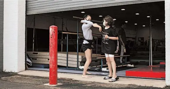  ?? ALYSSA SCHUKAR/THE NEW YORK TIMES ?? A summer camp staffer gives an elbow bump on July 9 at Dynamic Gymnastics in Falls Church, Virginia. Elbow bumps could be a long-term alternativ­e to handshakes or hugs.