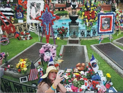 ?? MANDEL NGAN / AGENCE FRANCE-PRESSE ?? A fan takes a photo of herself at the Meditation Garden where Elvis Presley is buried alongside his parents and grandmothe­r at his Graceland mansion on Saturday in Memphis, Tennessee.