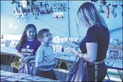  ??  ?? Las Vegan Mayra Barajas buys a video game for her nephew Steven Dominguez, 6, with his sister Alexa, 8, at the Broadacres Marketplac­e on Las Vegas Boulevard North.