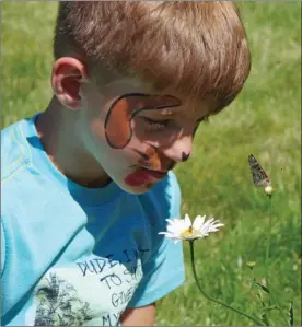  ?? BARB AGUIAR/Special to The Daily Courier ?? Reece Hogarth, 8, who was visiting from Georgetown, Ont., is fascinated by a butterfly in the garden at Falcon Ridge Farms in Kelowna during Sunday’s sixth annual Butterfly Effect fundraiser for the Central Okanagan Hospice Associatio­n.