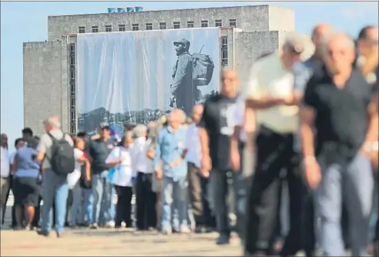  ?? CARLOS BARRIA / REUTERS ?? Una gran fotografía de Fidel Castro cuelga de un edificio en la plaza de la Revolución, donde la gente espera para despedirse del Comandante