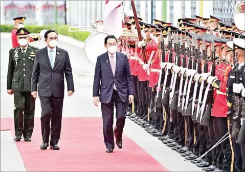  ?? AFP ?? Japanese Prime Minister Fumio Kishida (centre) and his Thai counterpar­t Prayut Chan-o-cha inspect the honour guard at the Government House in Bangkok on Monday.