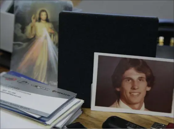  ?? STEVEN SENNE — THE ASSOCIATED PRESS ?? A photograph of Joseph LaCross, right, rests near an image of Jesus, left, on a desk belonging to Barrington, R.I., Police Chief John LaCross at the police station, in Barrington. Joseph LaCross committed suicide in 1979. Police Chief LaCross, who has...