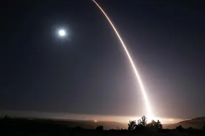  ?? Al Seib/Los Angeles Times/TNS ?? Streaking over the moon and the Pacific Ocean, the Minuteman III missile of Glory Trip GT-222 lights the sky, launched by the Air Force 576th Flight Test Squadron at Vandenberg Air Force Base, during an unarmed test launch at 12:02 a.m. May 3 from the...