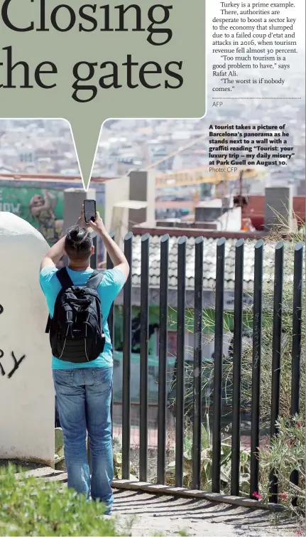  ?? Photo: CFP ?? A tourist takes a picture of Barcelona’s panorama as he stands next to a wall with a graffiti reading “Tourist: your luxury trip – my daily misery” at Park Guell on August 10.