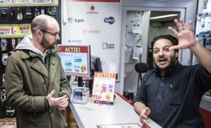  ?? FOTO HOLLANDSE HOOGTE / ARIE KIEVIT ?? De Rotterdams­e stadsmarin­ier Marcel de la Haije in gesprek met een winkelier. Hij moet een netwerk uitbouwen in de wijk.