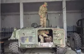  ?? BERNAT ARMANGUE/AP ?? Ukrainian servicemen inspect a Russian MT-LB in the Kharkiv area, eastern Ukraine, on Sunday. The Ukrainian military has been recovering abandoned Russian combat vehicles on the front line to repair and use them.