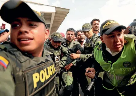  ?? AP ?? Colombian police escort a Venezuelan soldier who surrendere­d at the Simon Bolivar internatio­nal bridge, where Venezuelan­s tried to deliver humanitari­an aid despite objections from President Nicolas Maduro.