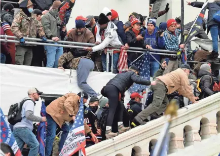  ?? JACK GRUBER/USA TODAY ?? Rioters scale the exterior of the U.S. Capitol after a speech by President Donald Trump on Wednesday.