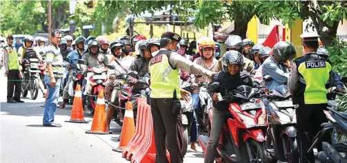  ?? AHMAD KHUSAINI/JAWA POS ?? FOKUS: Anggota Polsek Kenjeran memeriksa kelengkapa­n pengendara yang datang dari arah Suramadu. Ini dilakukan untuk mencegah pengendara yang melawan arus.