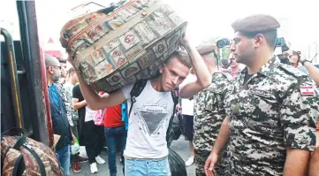  ??  ?? A Syrian man carries a luggage as refugees prepare to leave the Lebanese capital Beirut to return to their homes in Syria. — AFP photo