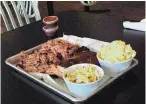  ??  ?? Ribs, brisket and pulled pork served with coleslaw and baked macaroni and cheese at The Hot Mess.