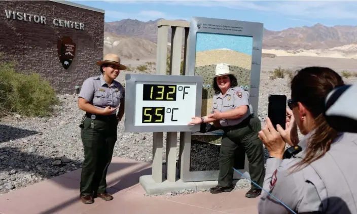  ?? Photograph: Ronda Churchill/AFP/Getty Images ?? National Park Service rangers are photograph­ed next to a digital display of an unofficial heat reading at Furnace Creek Visitor Center in Death Valley, California, on Sunday.