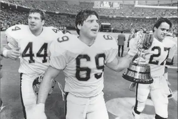  ?? HAMILTON SPECTATOR FILE PHOTO ?? Toronto Argonaut offensive lineman Dan Ferrone carries the Grey Cup as the Argos celebrate winning the 1983 CFL championsh­ip.