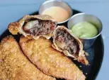  ?? Paul Stephen / Staff ?? These empanadas at Botika are stuffed with barbacoa, olives, peppers and potato.