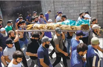  ?? Zurab Tsertsvadz­e Associated Press ?? MOURNERS in Georgia carry the body of the ethnic Chechen man killed on the streets of Berlin in August.