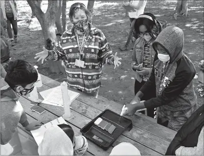  ?? Jeffrey F. Bill
/The Baltimore Sun /TNS ?? Sharon Gustin, volunteer naturalist, leads a group of sixth grade students from Murray Hill Middle School at the “Tree Canopy” station. Khalil Malloy, 11, is spraying water into a paint tray, simulating rain.the sponges represent a tree canopy planted on a hill.