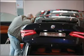  ?? (Bloomberg News/Krisztian Bocsi) ?? A customer peers inside a car window at a BMW AG showroom in Berlin.