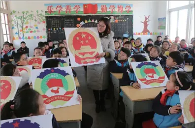  ??  ?? A teacher and students hold pictures of National Emblem of China and the logo of the Chinese People’s Political Consultati­ve Conference to learn about the two sessions at the Guanyun Experiment­al Primary School in Lianyungan­g city, East China’s Jiangsu...
