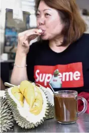  ??  ?? Good with a cuppa: A woman enjoying her durian with coffee.