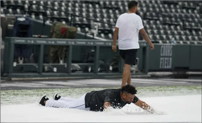  ?? DAVID ZALUBOWSKI — THE ASSOCIATED PRESS ?? Rockies catcher Elias Diaz, front, dives onto a hail-covered tarp after a summer storm packing heavy rain, high winds and large hail swept over Coors Field on Thursday.