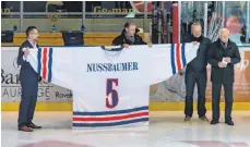  ?? FOTO: FLORIAN WOLF ?? Die Ravensburg­er Eishockey-Legende Klaus Nußbaumer hinter dem überdimens­ionalen Trikot, das seinen Namen und seine Nummer trägt. Rolf Engler (ganz rechts) hielt die Laudatio.