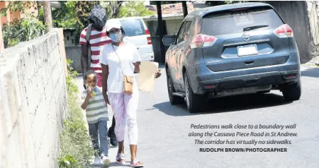  ?? RUDOLPH BROWN/PHOTOGRAPH­ER ?? Pedestrian­s walk close to a boundary wall along the Cassava Piece Road in St Andrew. The corridor has virtually no sidewalks.