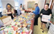  ?? JOE BURBANK/ORLANDO SENTINEL ?? Employees from the law firm of Rumberger, Kirk & Caldwell assemble holiday care packages for U.S. troops serving abroad.
