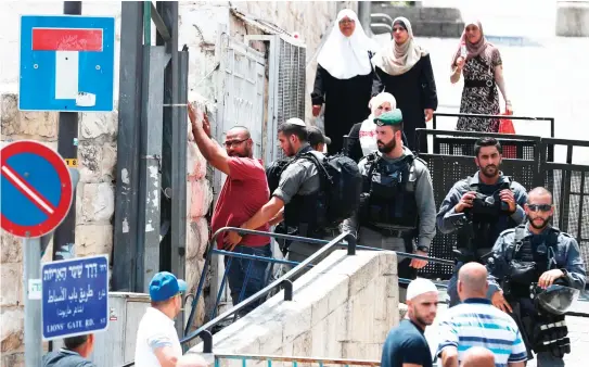  ??  ?? Israeli security forces frisk a Palestinia­n man outside Lions’ Gate, a main entrance to the Al-Aqsa mosque compound in Jerusalem’s Old City on Saturday. (AFP)